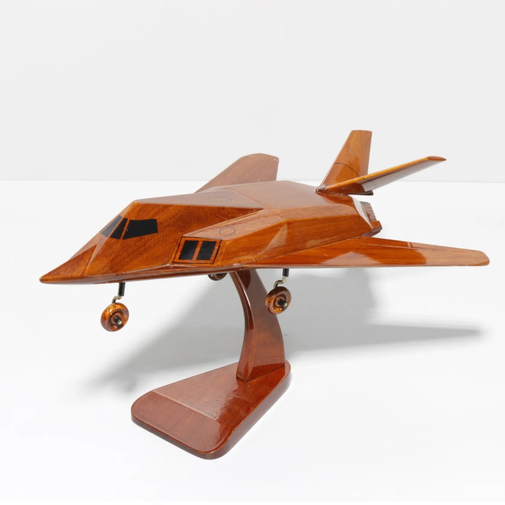 Angled front-left perspective of F-117 stealth wooden model on stand